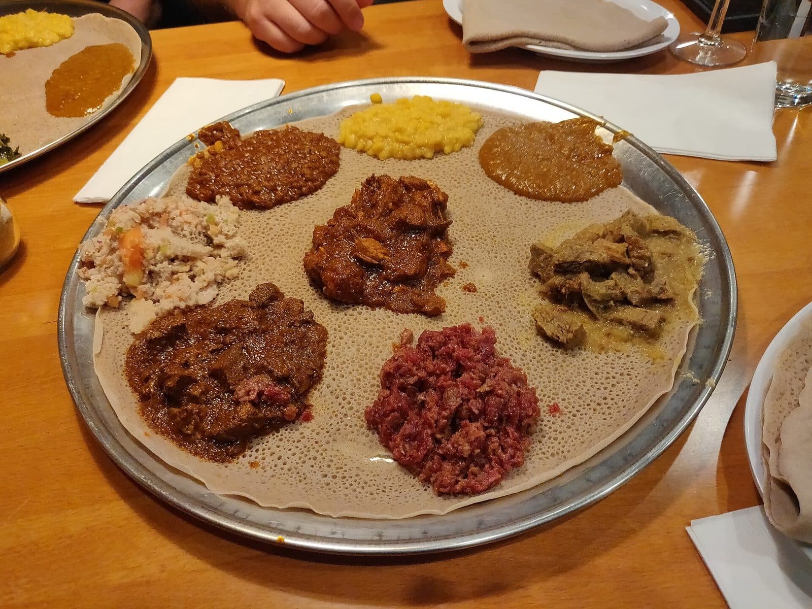 Mehrere Gedecke rund um eine gemeinsame Injera-Platte