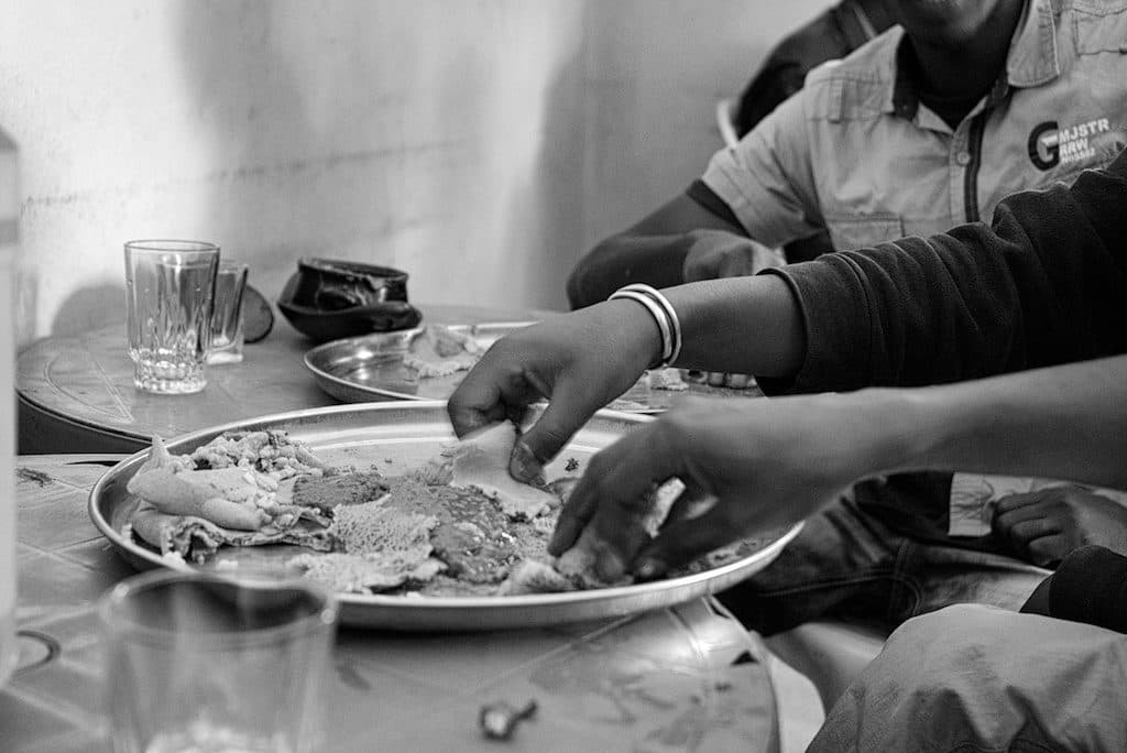 Mehrere Hände greifen gemeinsam nach Injera