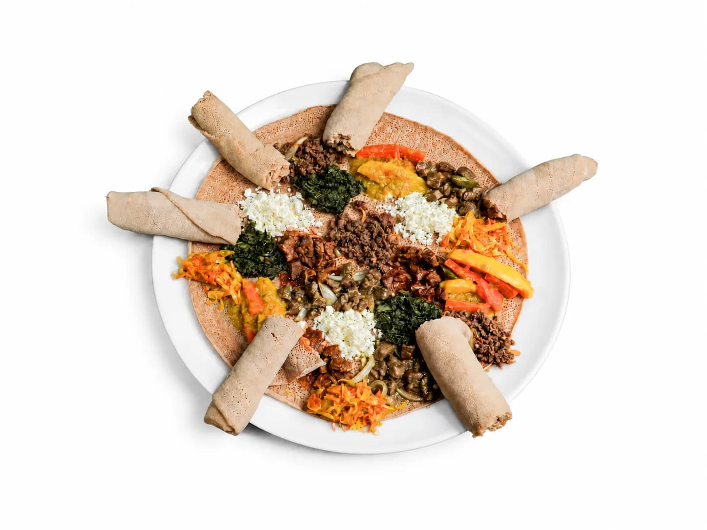Round mixed platter with several dishes and rolled injera
