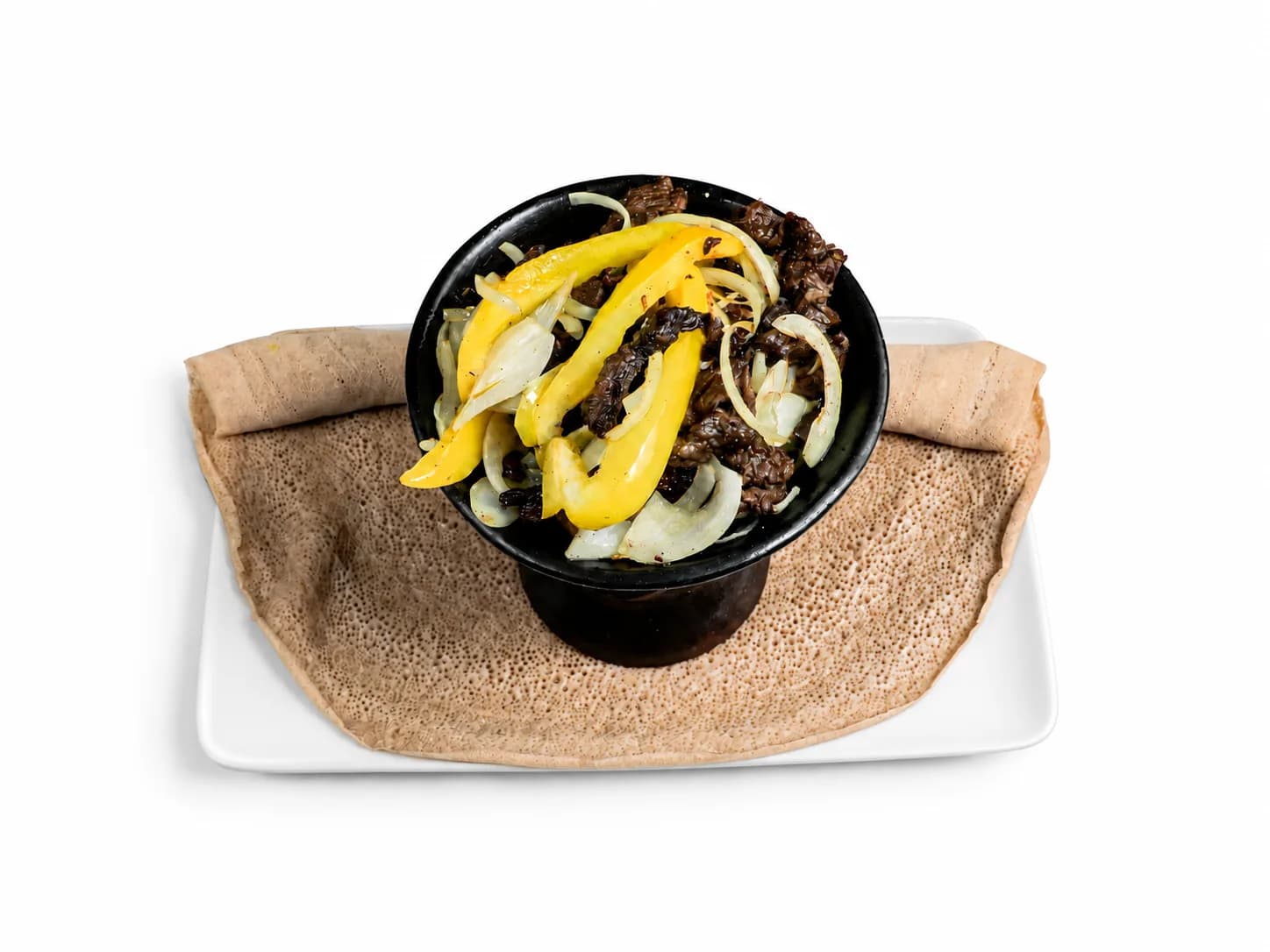 Zilzil Tibs with onions and yellow chilli on injera