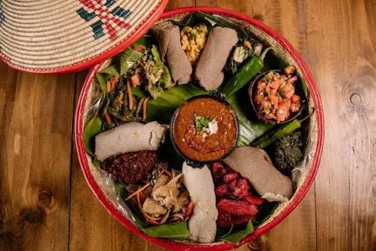 Gedeckter Tisch mit Injera und mehreren Gerichten zum Teilen