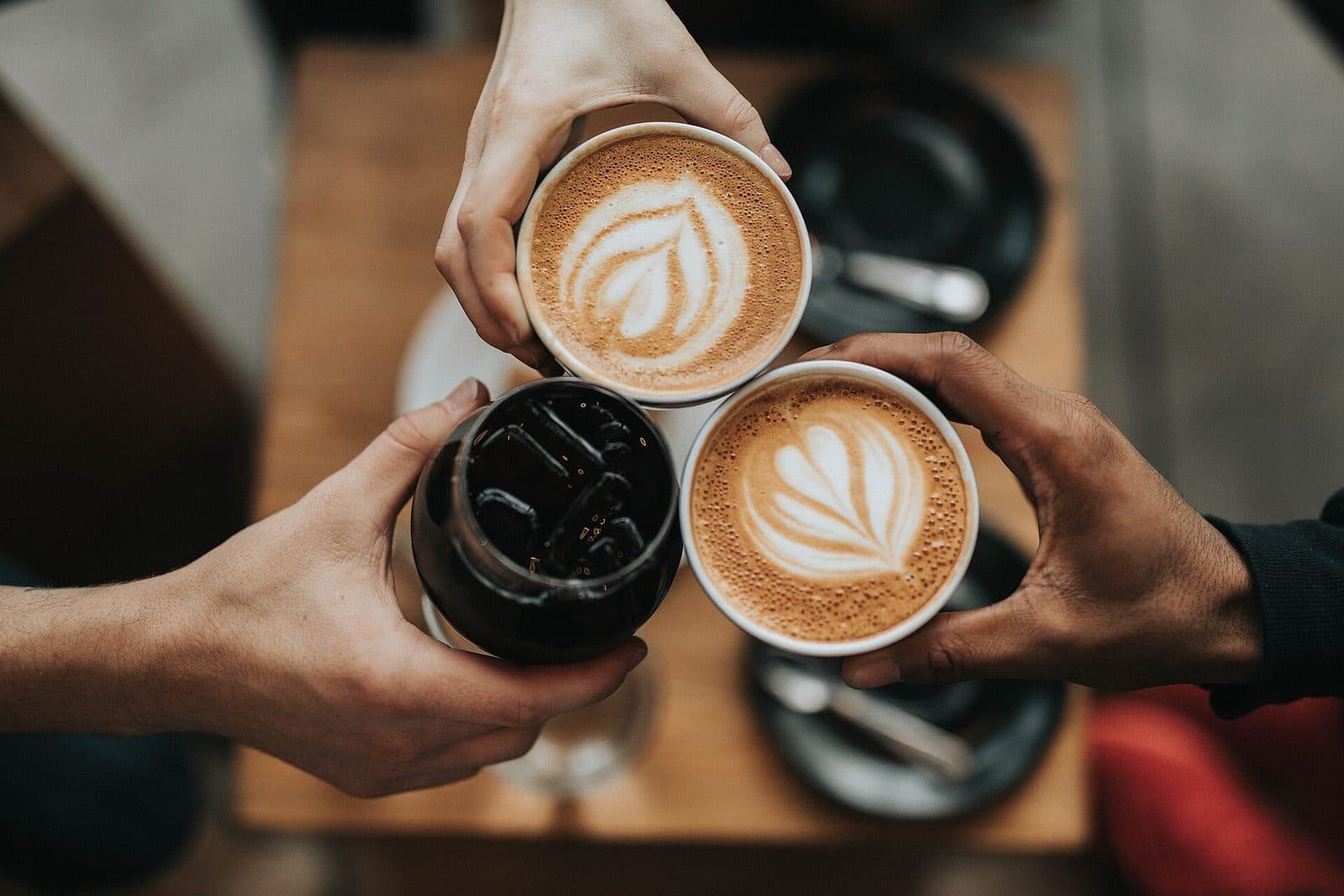 Zwei Hände stoßen mit Kaffeetassen an