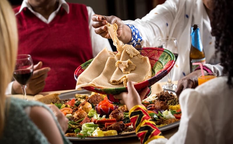 Eine Gruppe isst gemeinsam von einer großen Injera-Platte