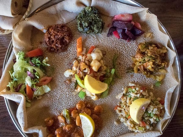 Gäste teilen sich eine Injera-Platte an einem Tisch